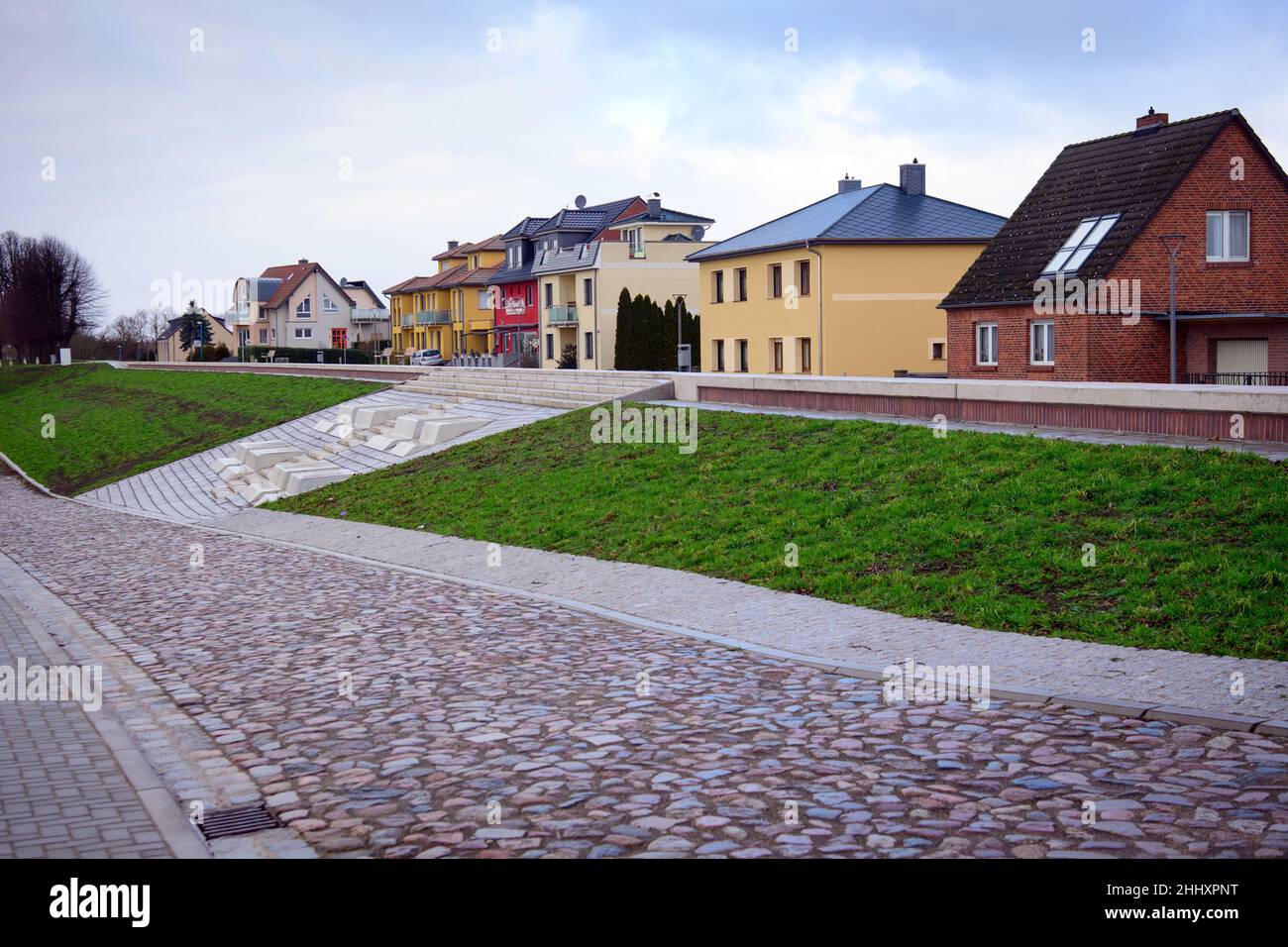 17. Januar 2022, Brandenburg, Wittenberge: Am Elbufer wurde in der Nähe der Pension zur Möwe ein bewachsener Elbdeich errichtet. Die Vorarbeiten für den Hochwasserschutz und den Straßenausbau im Bereich der Elbstraße hatten 2019 begonnen. Das Hochwasserschutzsystem wurde 2021 fertiggestellt und erhöht die Sickerlichkeit der Altstadt mit Zugang zum Nedwigshafen und den Räumlichkeiten der Wasser- und Schifffahrtsbehörde. Im Katastrophenfall kann eine mobile Hochwasserschutzwand errichtet werden, die vor Überschwemmungen bis zu einer Höhe von 7,99 Metern schützt. Foto: Soeren Sache/dpa-Zentralbild Stockfoto