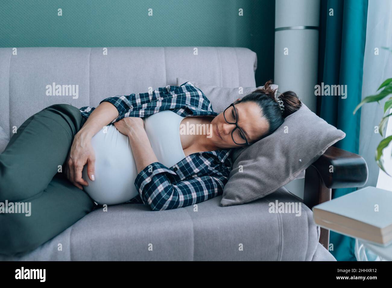 Schwangerin liegt auf der Couch. Kontraktionen, braxton hicks Stockfoto