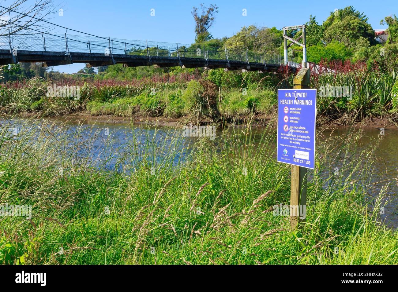 Ein Warnschild vor Wasserverschmutzung neben einem Bach in Tauranga, Neuseeland. Das zweisprachige Schild ist in Englisch und Maori geschrieben Stockfoto