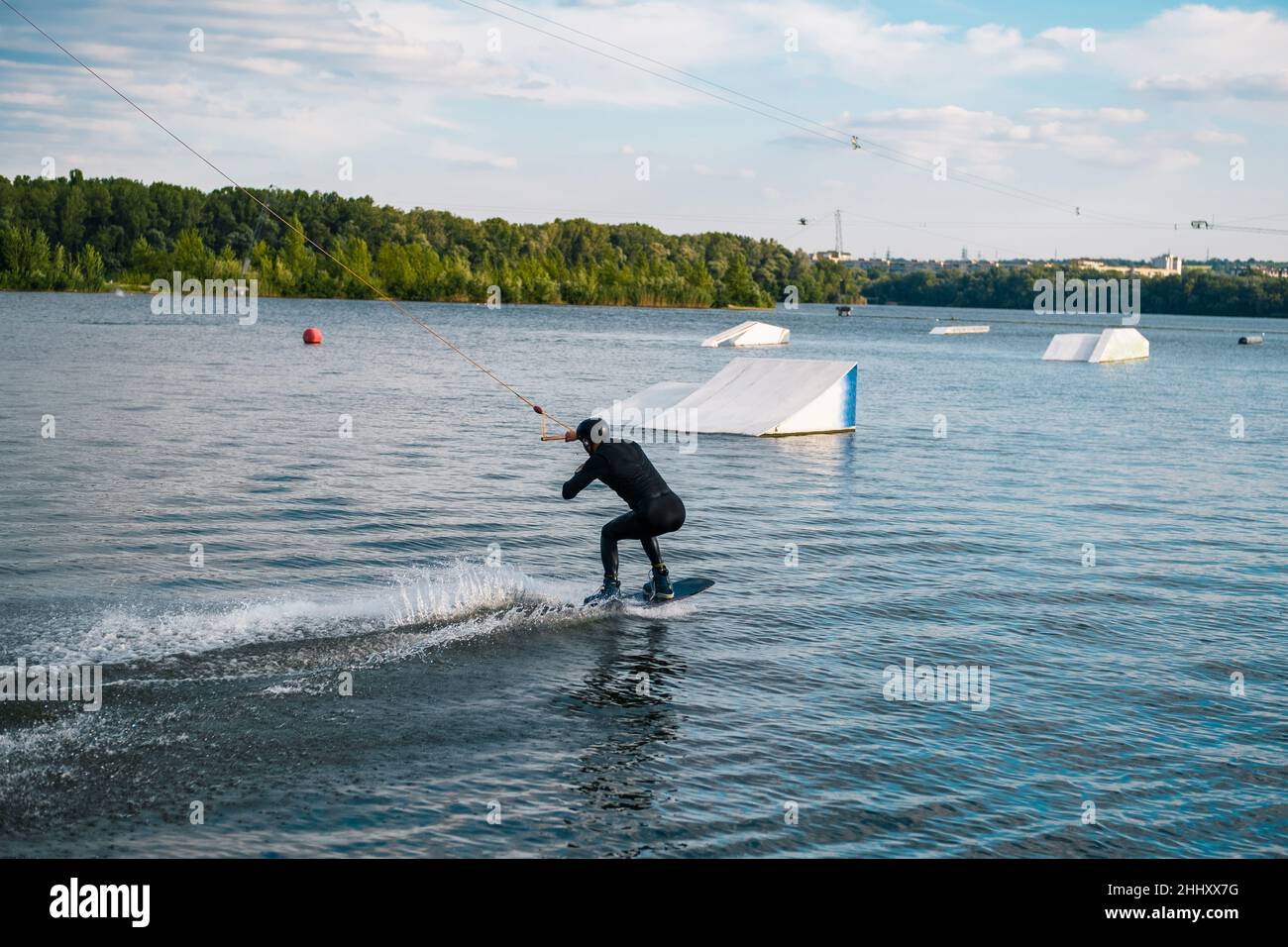 Wakeboarder rutscht auf dem Wasser an Bord und bereitet sich auf einen Rampensprung vor Stockfoto