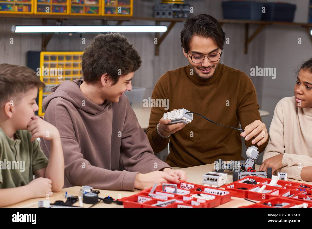 Junge Lehrer Engineering Roboter modelliert zusammen mit Studenten am Tisch im Klassenzimmer Stockfoto