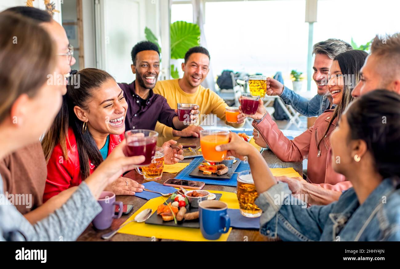Multirassische Gruppe von Menschen, die in einem Restaurant an der Tischbar sitzen und zusammen ein englisches Brunch-Frühstück genießen, reden und Spaß haben, zu lachen. Freunde Stockfoto