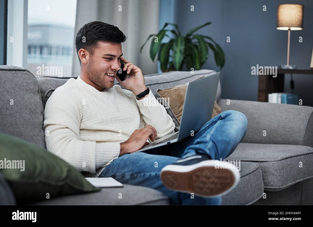 Vom Tisch aus in die Arbeit. Aufnahme eines jungen Mannes, der von zu Hause aus einen Laptop und ein Smartphone verwendet. Stockfoto