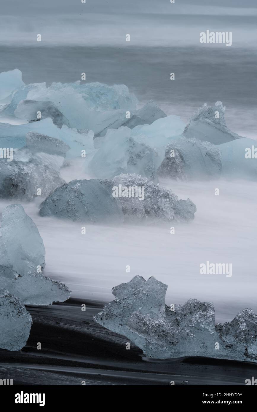 Eisberge über dunklem Jokulsarlon-Strand, vertikale Komposition Stockfoto