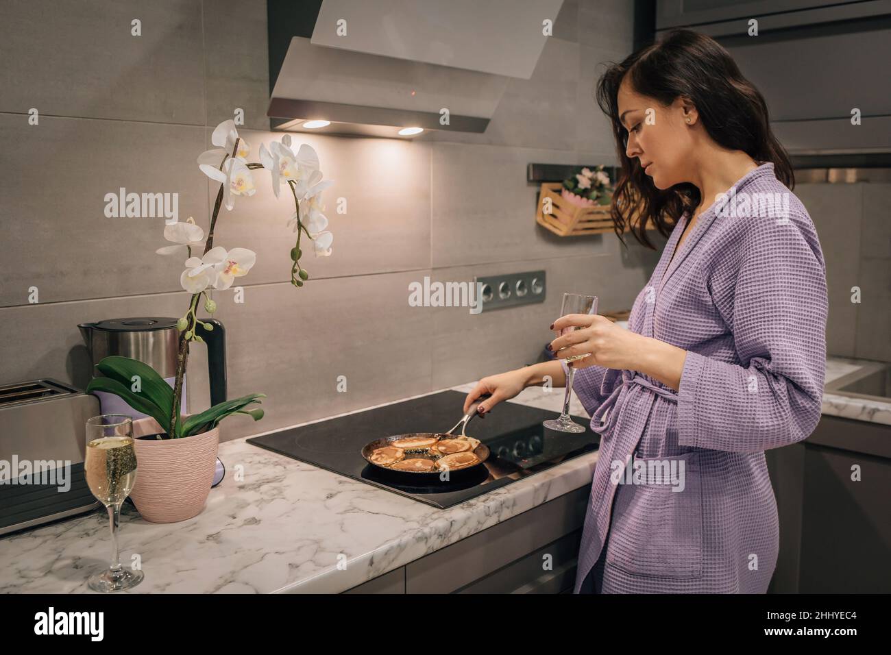 Junge Frauen in der Küche backen Pfannkuchen, Gebäck in der Pfanne auf dem Herd. Lifestyle-Konzept des Kochens zu Hause. Stockfoto