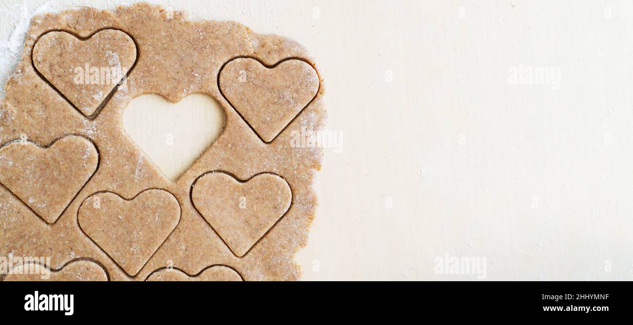 Der Prozess der Herstellung von herzförmigen Vollkornmehl-Cookies. Das Konzept des festlichen Hausbackens. Valentinstag. Draufsicht. Banner. Speicherplatz kopieren. Stockfoto