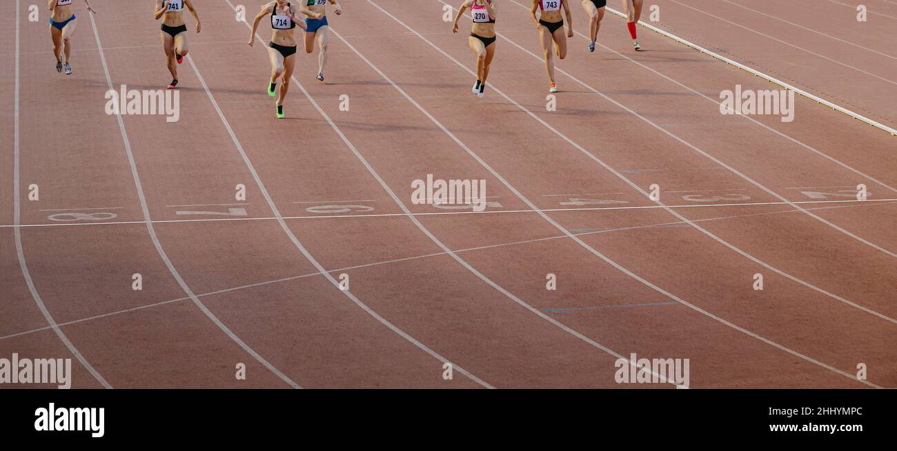 Weibliche Gruppenathleten laufen im Stadion als Ziellinie Stockfoto