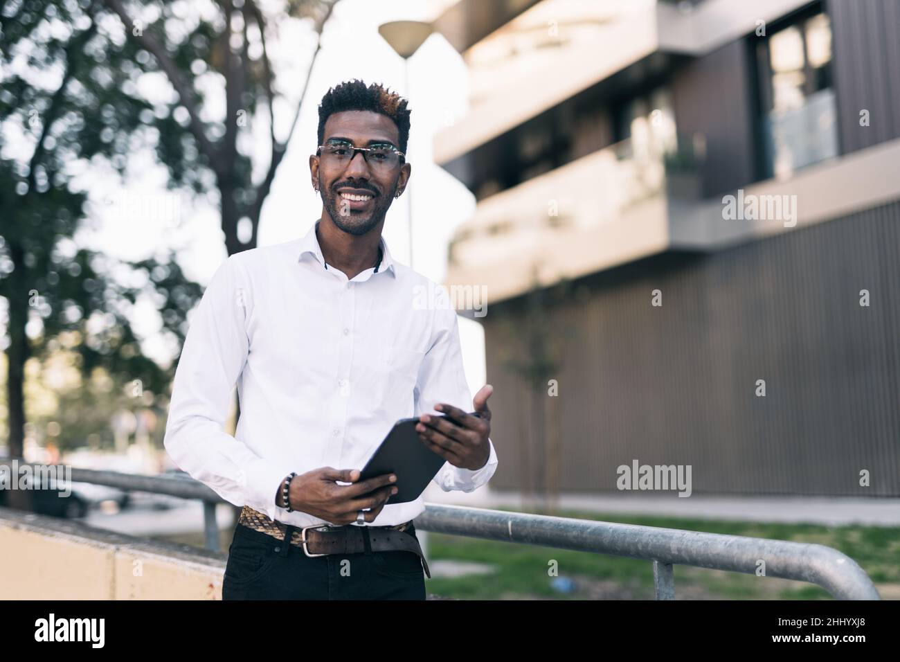 Porträt eines lächelnden jungen schwarzen Geschäftsmannes, der ein Tablet mit den Händen hält Stockfoto