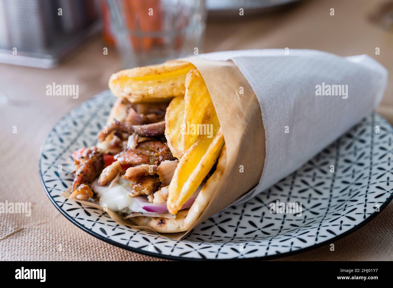 Traditionelle griechische Küche Gyros Pita mit Pommes frites, Gemüse und Tzatziki-Sauce. Nahaufnahme eines Kebab-Sandwiches auf Kreta, Griechenland. Traditionelle griechische Küche. Stockfoto