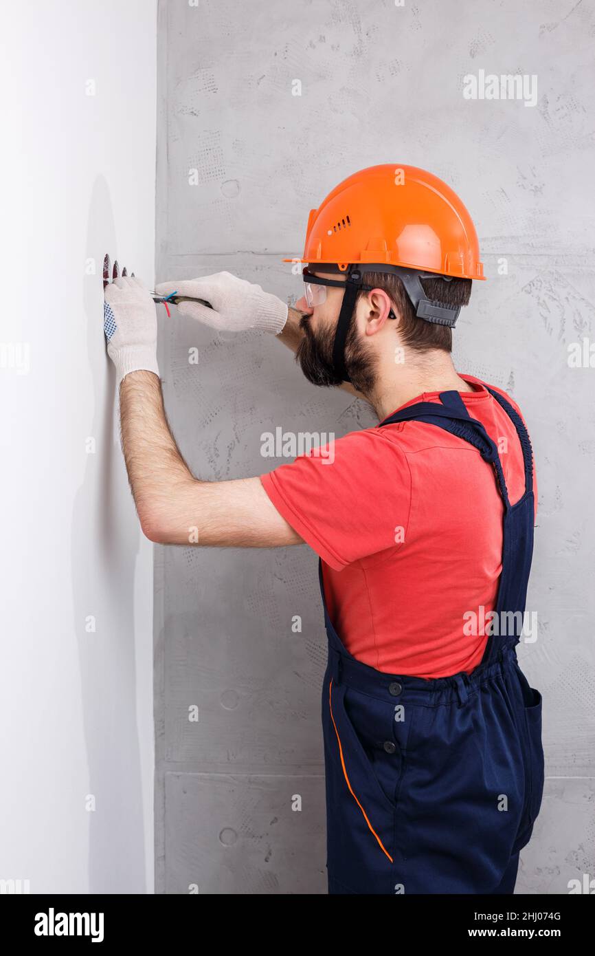 Elektriker im Helm installiert Steckdosen Stockfoto