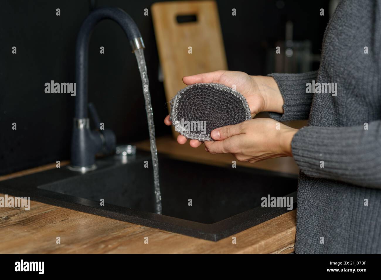 Hand hält natürliche wiederverwendbare handgestrickte Jute Waschlappen in der Küche Stockfoto