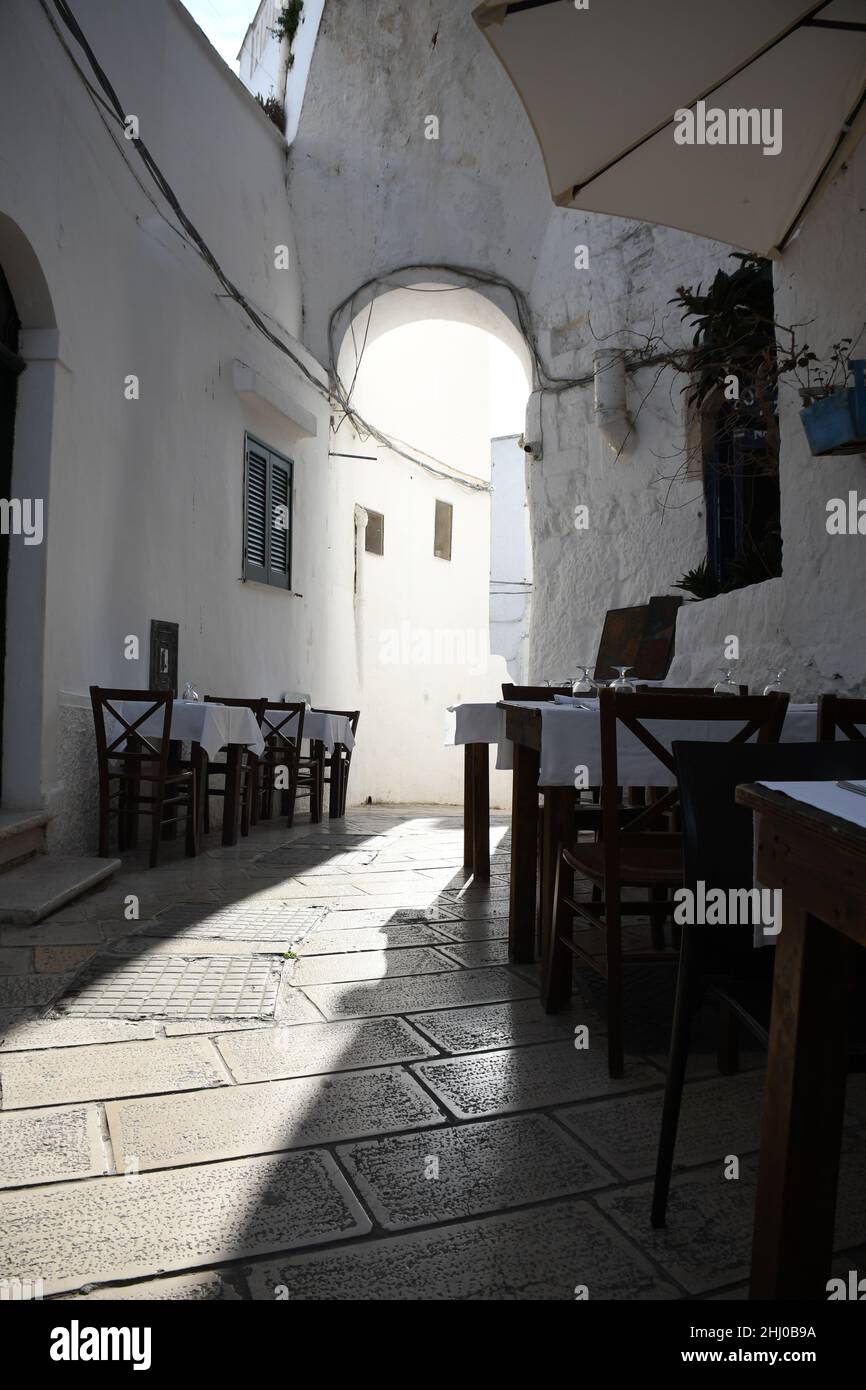 Tische und Stühle vor einem Restaurant in der Altstadt von Ostuni, auch bekannt als "die weiße Stadt", Apulien (Italien) Stockfoto