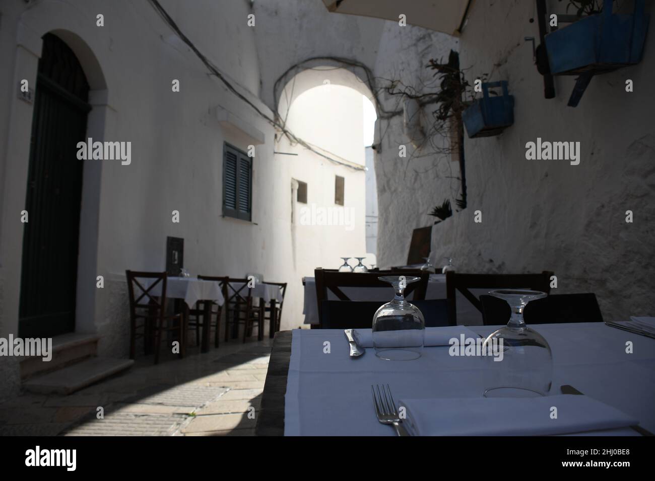Tische und Stühle vor einem Restaurant in der Altstadt von Ostuni, auch bekannt als "die weiße Stadt", Apulien (Italien) Stockfoto
