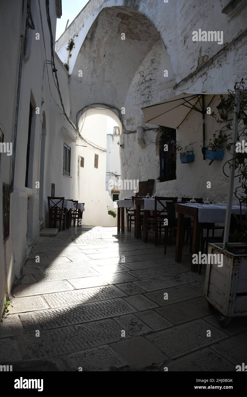 Tische und Stühle vor einem Restaurant in der Altstadt von Ostuni, auch bekannt als "die weiße Stadt", Apulien (Italien) Stockfoto