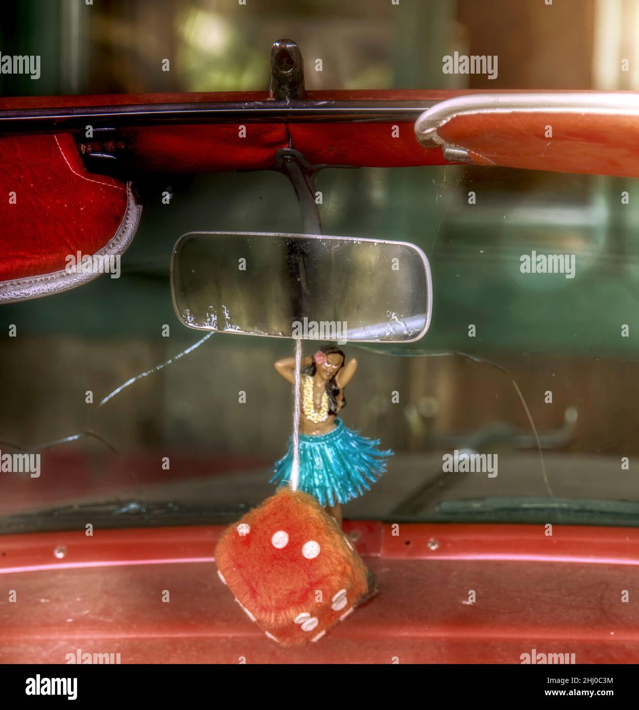 Nostalgisches rotes Cabrio mit Hula Girl und unscharfem Würfel Stockfoto