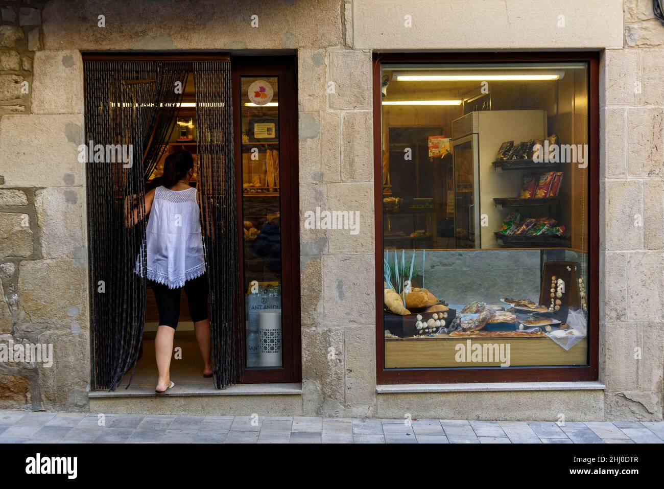 Eine Frau, die in eine Bäckerei in der Stadt Prats de Lluçanès (Osona, Barcelona, Katalonien, Spanien) eingeht ESP: Una mujer entrando en una panadería de un Pueblo Stockfoto