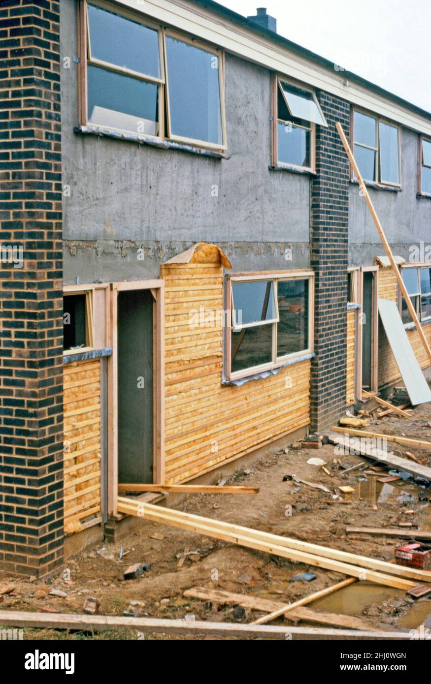 Moderner Hausbau in Stevenage New Town, Hertfordshire, England, Großbritannien im Jahr 1963. Hier wird an den Fronten einer Terrasse aus Häusern die Dämmung (nach modernen Standards dünn) durch Holzlatten gehalten, bevor eine aufgehängte Fliesenschicht aufgebracht wird – siehe Alamy 2HJ0WDC für die Arbeiter, die die Fliesen auftragen. Stevenage liegt etwa 30 Meilen (50 km) nördlich von London. Im Jahr 1946 wurde Stevenage nach dem New Towns Act zur ersten Neustadt Großbritanniens ernannt. Dieses Bild stammt aus einer alten Amateur-Farbtransparenz – einem Vintage-Foto aus dem Jahr 1960s. Stockfoto