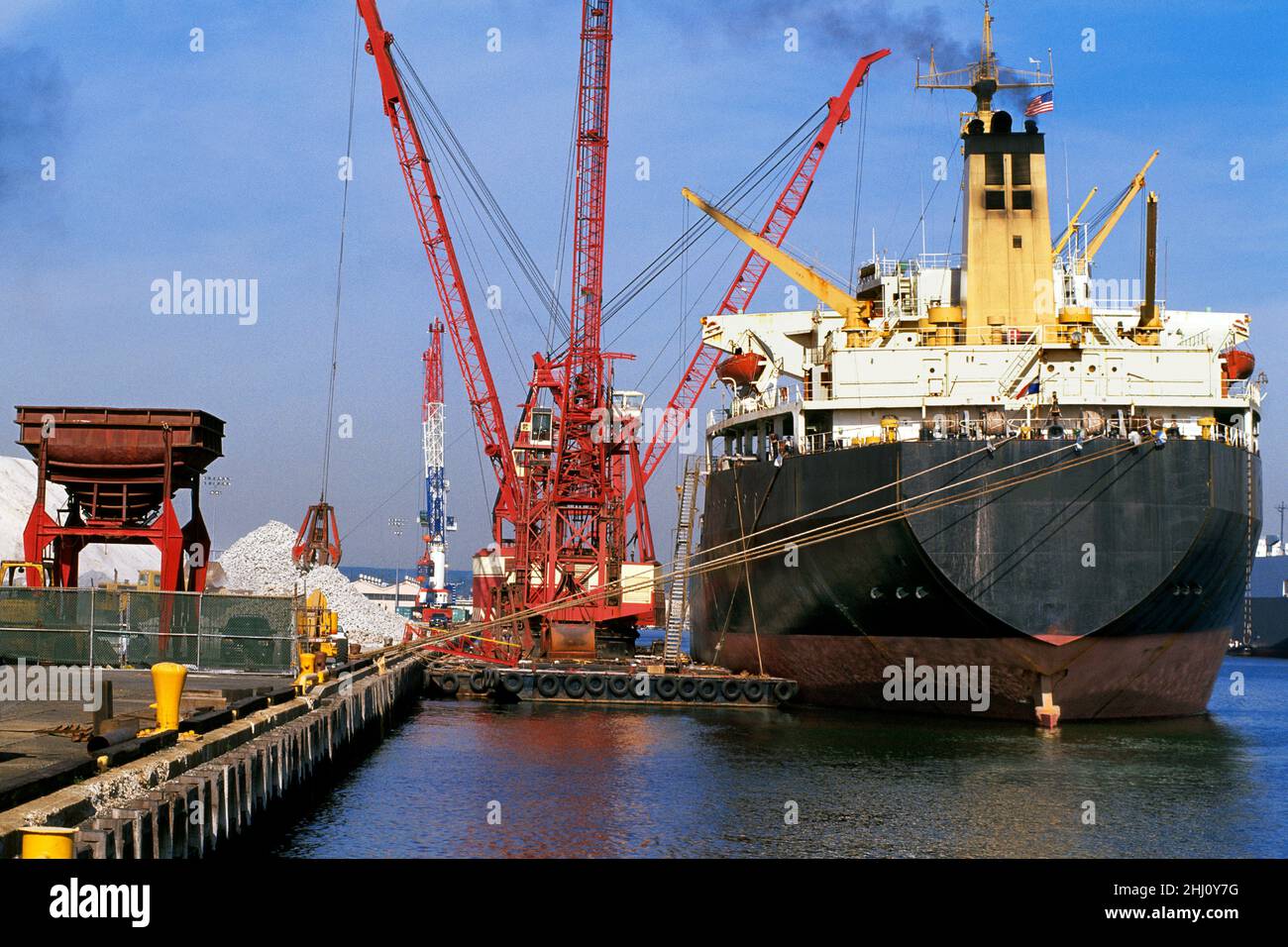 Frachtschiff im Hafen (Hafen). Industrielle Hafenladekräne, die Roherz für den Versand transportieren. Infrastruktur Port Elizabeth, Hafenbehörde, USA Stockfoto