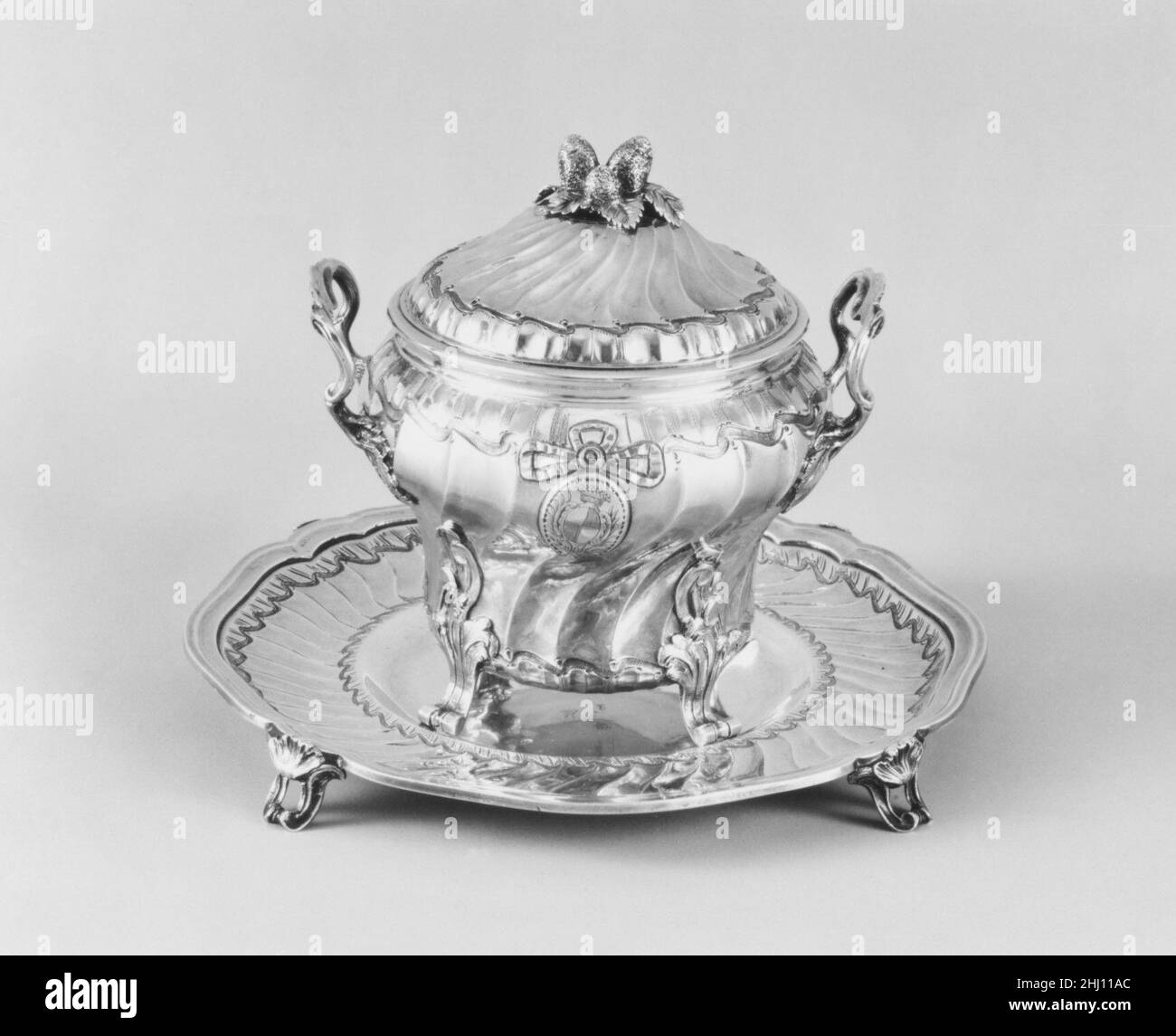 Zuckerdose mit Deckel und Tablett 1777–78 Alexandre de Roussy, die jüngeren Europäer, betrachteten Zucker als eine wesentliche Ergänzung zu Schokolade, Kaffee und Tee. Für Tee und Kaffee wurde Zucker häufig hinzugefügt, sobald das Getränk gegossen wurde. Zuckerschalen wurden schließlich in koordinierte Dienste integriert. Als importiertes gut war Zucker in Europa bis weit ins 19. Jahrhundert hinein teuer. Seine Bedeutung und Kosten spiegeln sich in dieser silbernen Schale und Ständer im Rokoko-Stil ausgeführt.. Zuckerdose mit Deckel und Tablett 200263 Stockfoto