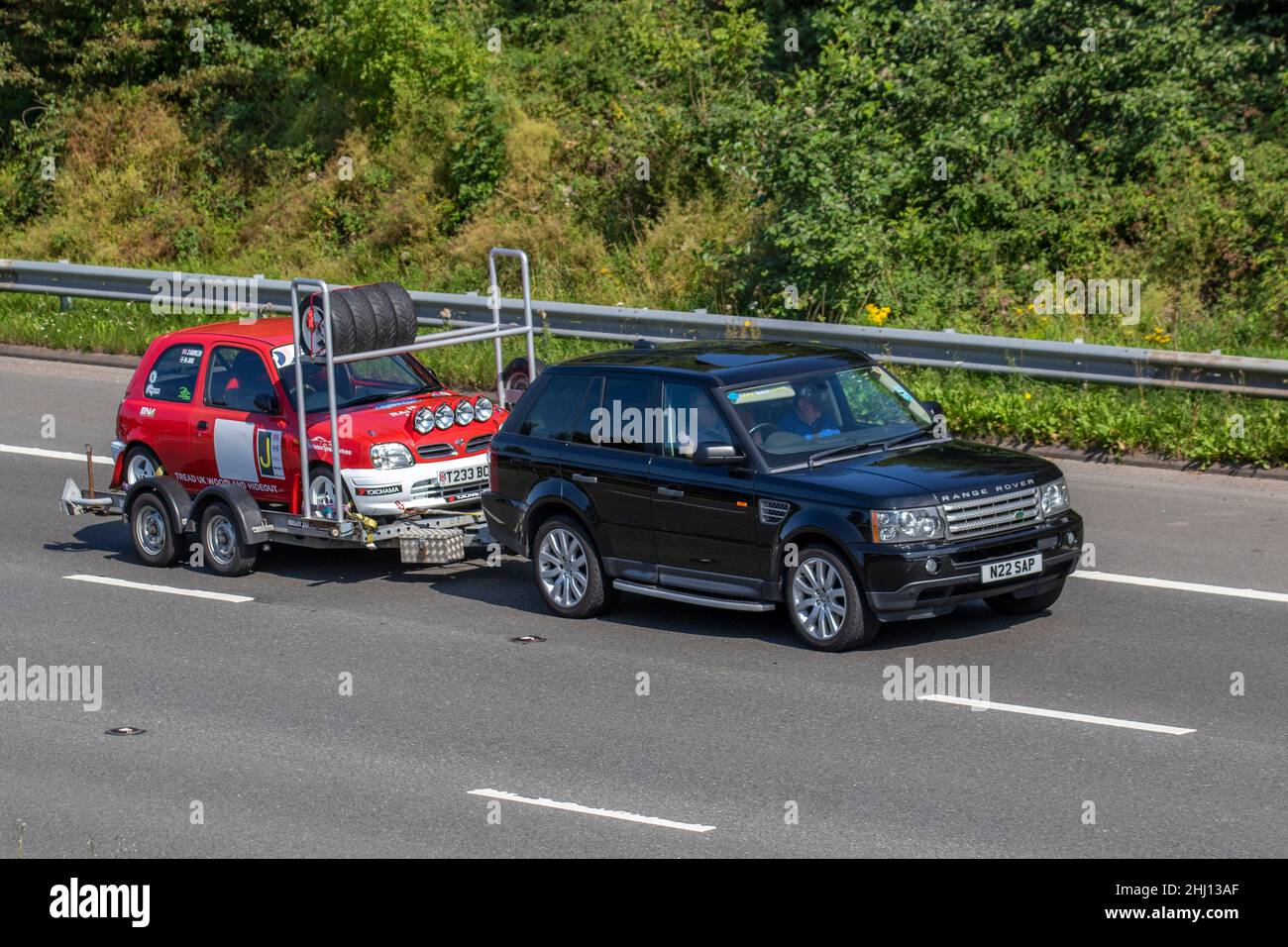 2008 Black Land Range Rover Sport 3628cc 6-Gang sequentielles automatisches Abschleppen 1999 rote Rallye Nissan Micra Inspiration 16V Auto auf r zweirädrigen Anhänger; Fahrzeugverkehr, bewegte Fahrzeuge, Autos, Fahrzeug fahren auf britischen Straßen, Motoren, Fahren auf der Autobahn M6 Autobahn UK Straßennetz. Stockfoto