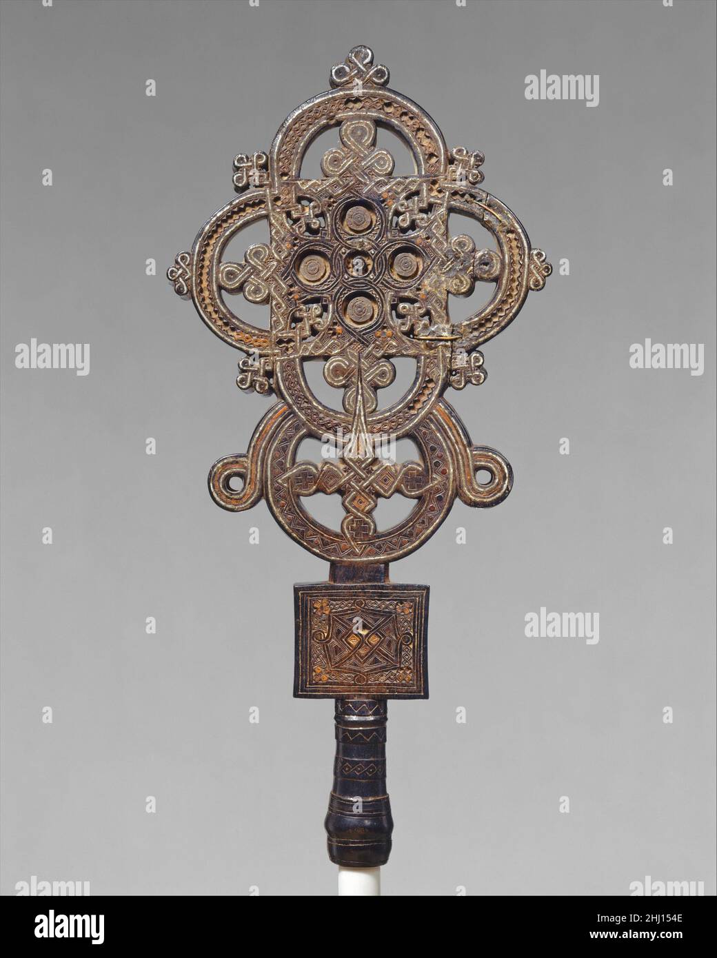 Prozessionskreuz ca. 1500 Ezra Dieses Kreuz wurde in der Provinz Tigray in der Nähe des Roten Meeres geschaffen, dem Geburtsort des frühesten Königreichs Äthiopiens und des Christentums in Afrika. Ein kleiner Korpus äthiopischer christlicher Werke aus der Zeit vor dem 17. Jahrhundert ist erhalten geblieben. Diese außergewöhnliche Kreation, in der ein höchst ungewöhnliches Zusammenspiel von Materialien reiche klangliche Kontraste bietet, ist eine Tour de Force. Die Festigkeit der geschnitzten Holzstruktur wird durch fein aufgebrachte Metalleinlagen durchdrungen. Die Komplexität dieser Arbeit, mit jeder Seite aufwändig voneinander unterschieden, ist unübertroffen. Es wurde Ezra zugeschrieben (ca. Stockfoto