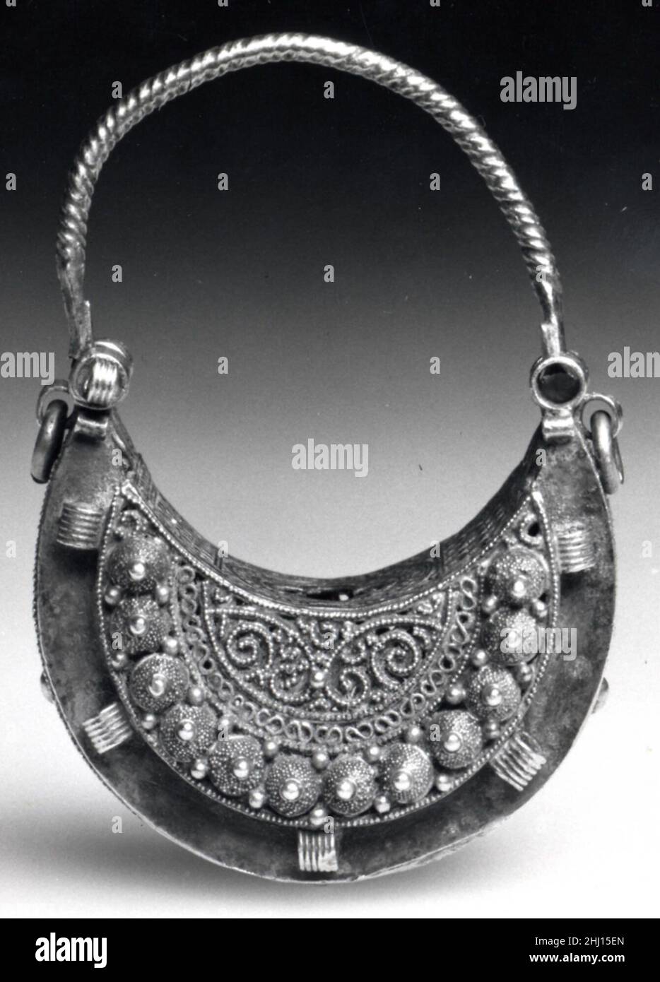 Ohrring 11th Jahrhundert dieser halbmondförmige (hilal) Ohrring wurde mit filigraner, perlenförmiger Granulation und mehreren Schleifen um den Umfang und das Innere hergestellt, die einst Edelsteine anfügten. Diese Merkmale, zusammen mit dem hemisphäre Ornament, sind typisch für den opulenten Schmuck aus der Fatimiden-Zeit (909–1171). Die Fatimiden regierten ein Königreich, das sich über Nordafrika, die Levante und Hijaz erstreckte und bis nach Nubia, dem heutigen Sudan, reichte, wo sie die Kontrolle über die wichtigen Goldminen behielt, die die Rohstoffe lieferten, die für die Herstellung dieser prächtigen Juwelen erforderlich waren. Diesen Ohrring Stockfoto