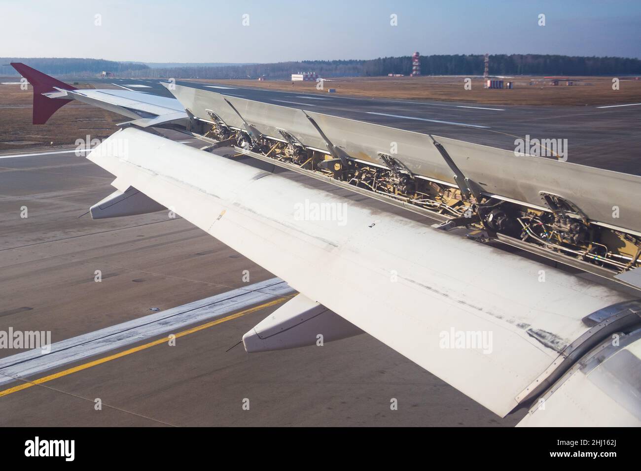 Der Flügel eines Passagierflugzeugs mit Luftbremsen und Mechanisierung unter ihnen an den Klappen nach der Landung Stockfoto