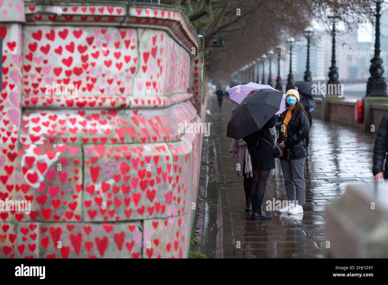 Fußgänger werden an der National Covid Memorial Wall in London neben roten Herzen, die diejenigen darstellen, die an Covid-19 gestorben sind, gesehen. Stockfoto