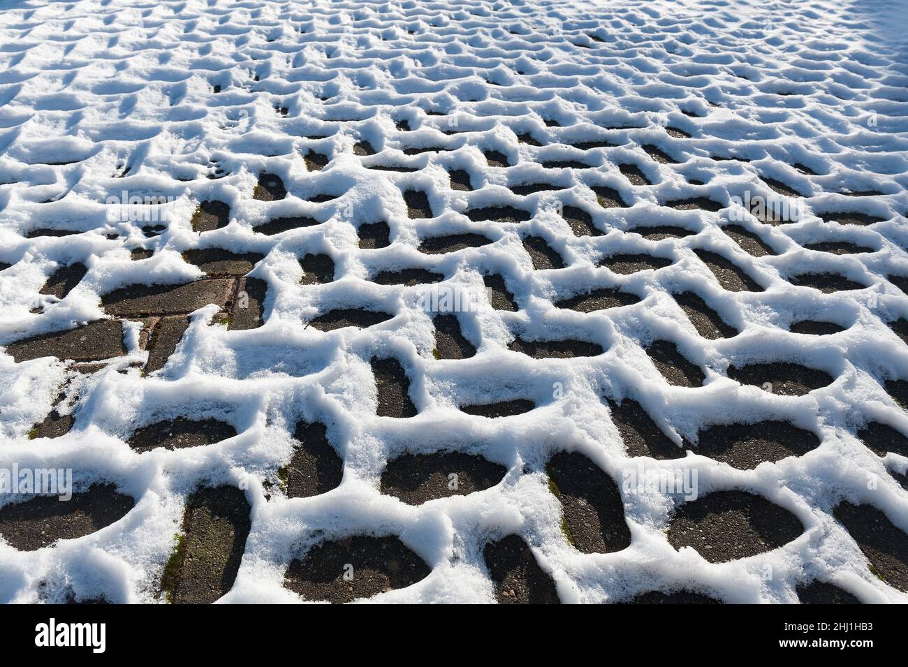 Sich wiederholende Fischgrätschneemuster, die durch Leitungsunterschiede entstehen, Wärmedämmung in der Auffahrt dunkle Bereiche werden sich durch Sonneneinstrahlung schneller erwärmen Stockfoto