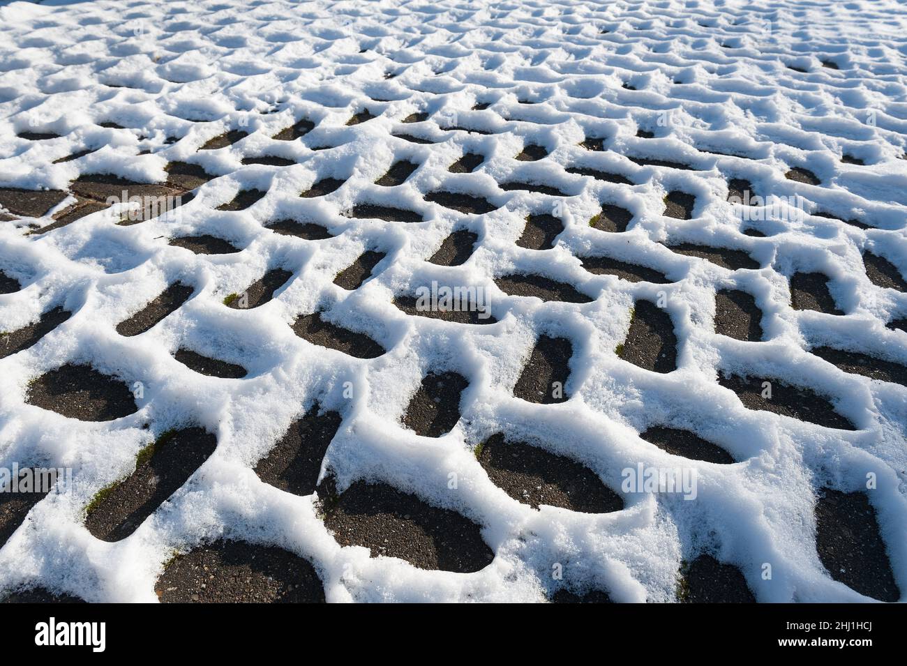 Sich wiederholende Fischgrätschneemuster, die durch Leitungsunterschiede entstehen, Wärmedämmung in der Auffahrt dunkle Bereiche werden sich durch Sonneneinstrahlung schneller erwärmen Stockfoto