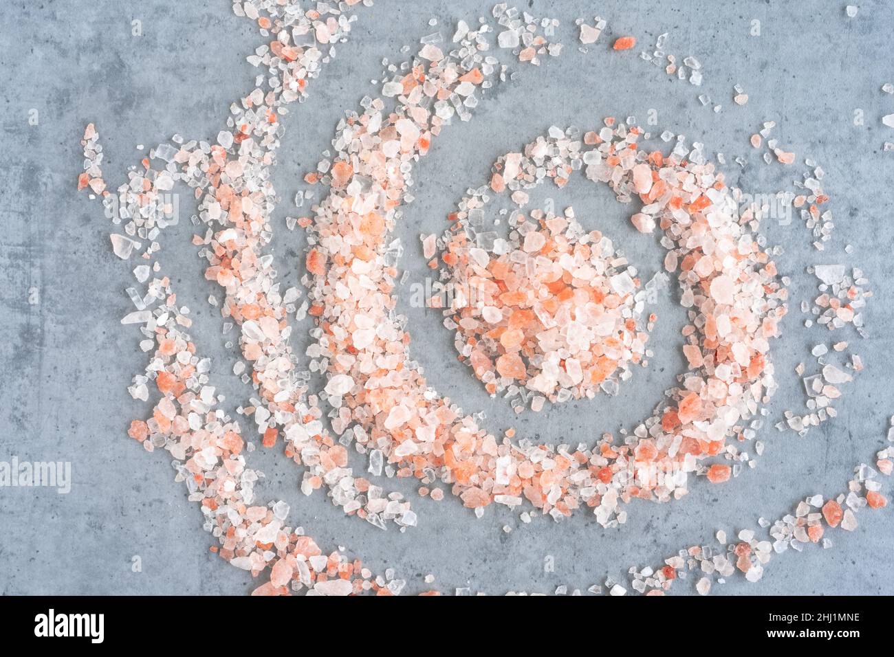 Himalaya-Salz spiralförmig auf grauem Hintergrund gestreut, Draufsicht Stockfoto