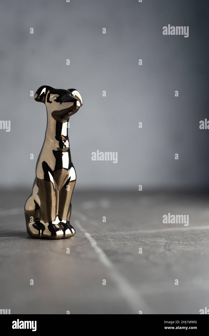 Сhrome-plattierte Metallstatuette eines Hundes, isoliert auf einem dunklen neutralen Hintergrund Stockfoto