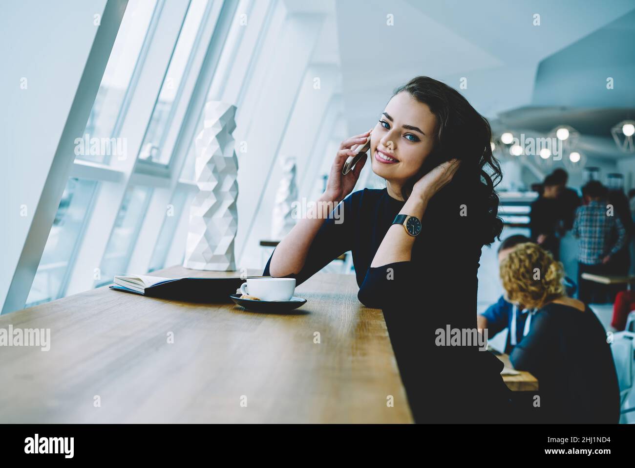 Glückliche Frau, die am Telefon sprach und Haare berührte Stockfoto