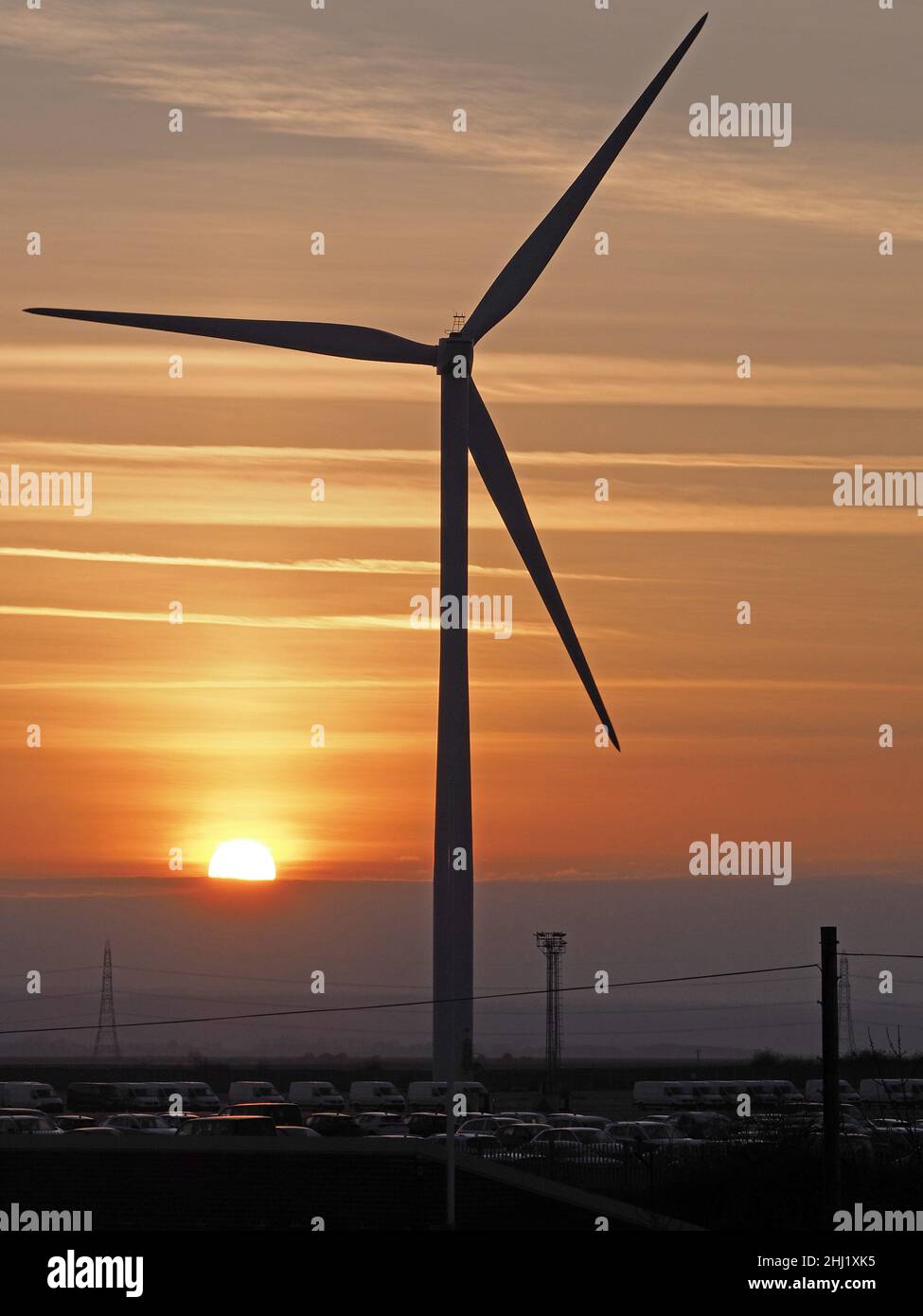 Sheerness, Kent, Großbritannien. 26th Januar 2022. UK Wetter: Sonnenuntergang in Sheerness, Kent hinter einer Windturbine und Autos in Sheerness Docks. Hafenarbeiter, die Autos abfertigung, planen, morgen wieder zu streiken. Kredit: James Bell/Alamy Live Nachrichten Stockfoto