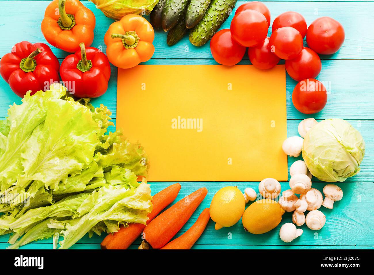 Gemüserahmen mit orangefarbenem Rezepturpapier auf blauem Holzhintergrund. Draufsicht Stockfoto