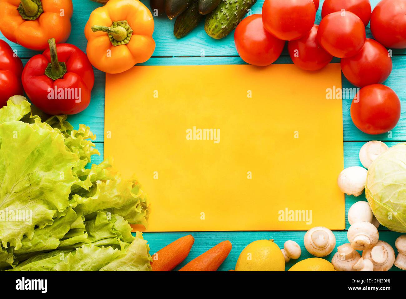 Gemüserahmen mit orangefarbenem Rezepturpapier auf blauem Holzhintergrund. Draufsicht Stockfoto