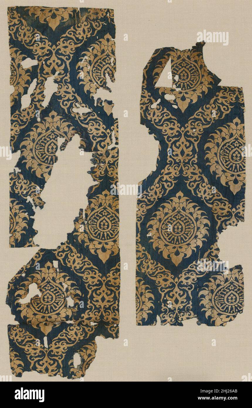 Textile Fragment mit ogivalem Muster 14th. Jahrhundert Dieses Fragment wurde von chinesischen und mongolischen Prototypen beeinflusst und zeigt ein sich wiederholendes Muster einer ogivalen Weinrolle, die sich um Lotusblüten im chinesischen Stil mit einer Naskh-Inschrift wellt. Die Inschrift lautet im Spiegelbild „der Sultan, der König“, ein Verweis auf einen unbenannten mamlukischen Sultan. Die Kombination dieser Elemente – der östliche Ursprung des Designs, eine Inschrift, die die herrschende Elite anruft, und die Pracht des Gewebes – waren die häufigsten Merkmale von Luxustextilien der Zeit und die visuelle Manifestation der Stockfoto