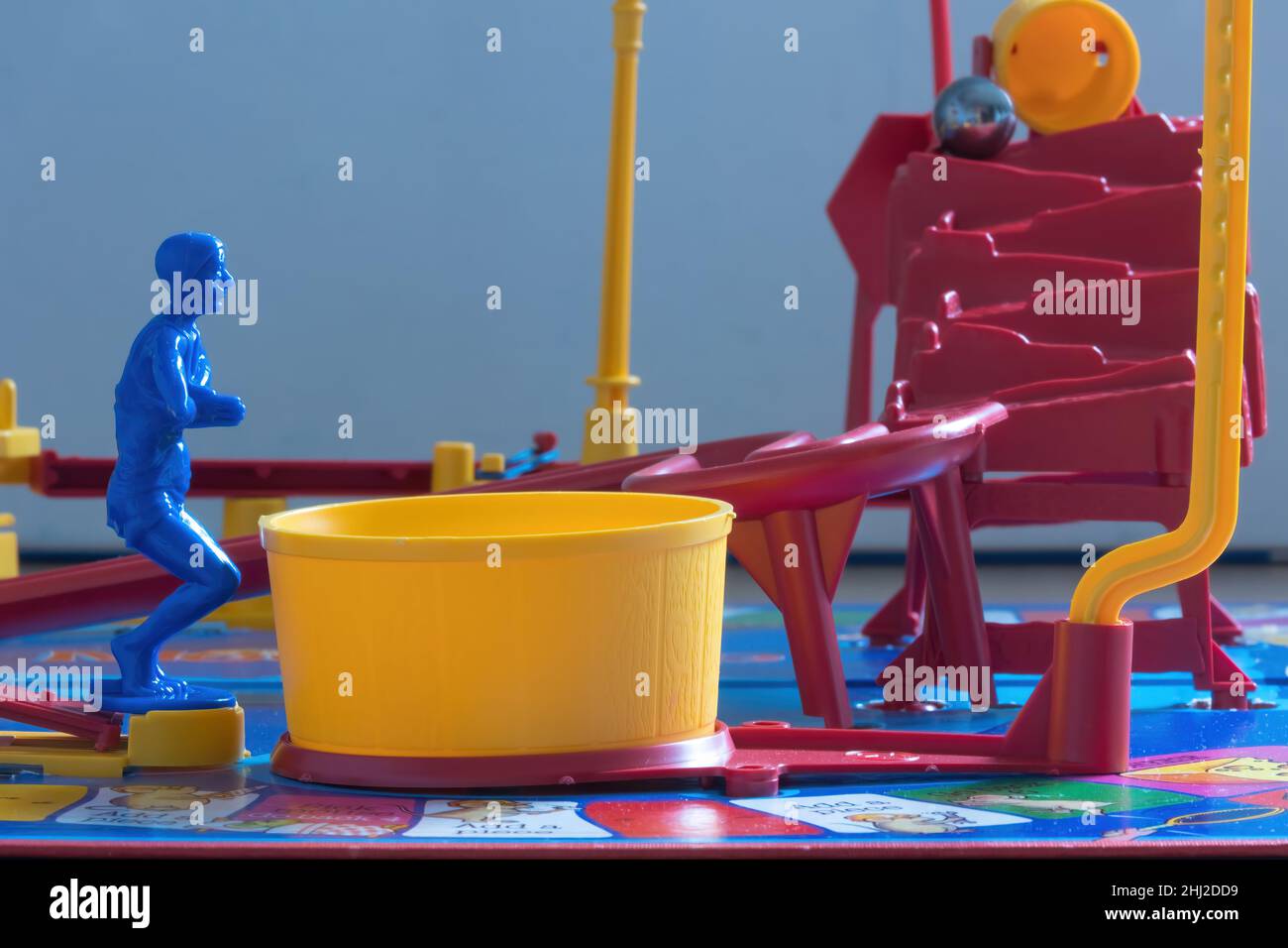 Nahaufnahme des Diver on Mouse Trap Board Spiel bereit, um in den gelben Pool zu tauchen, der die Mausfalle einrichtet.die Eimer kippen die Stahlkugel heraus. Stockfoto