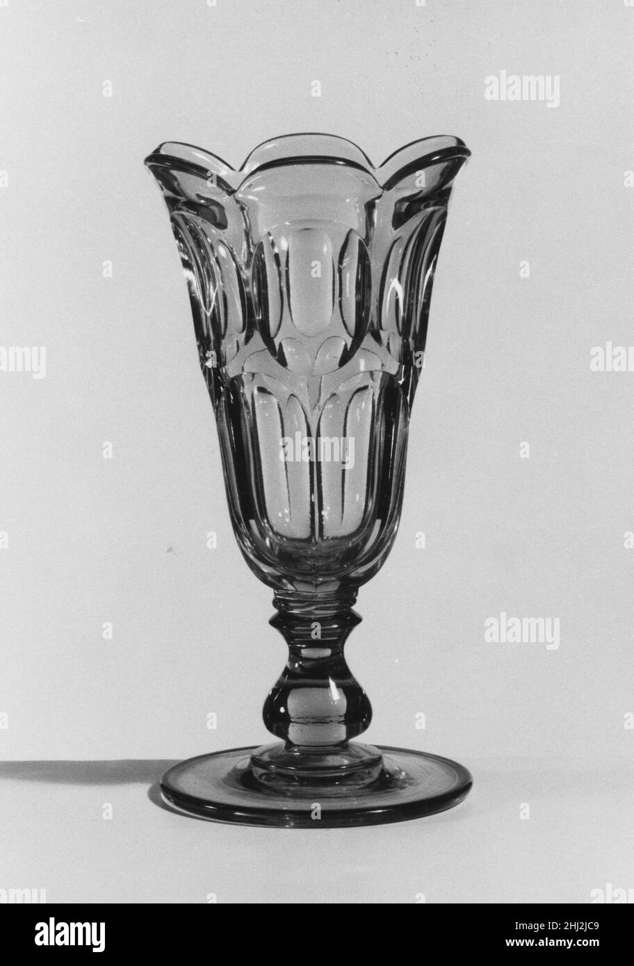 Sellerie Vase 1840–50 Amerikaner mit der Entwicklung neuer Formeln und Techniken hatte sich die Technologie des Glaspressens Ende 1840s deutlich verbessert. Zu dieser Zeit wurden gepresste Tischdecken in großen, passenden Sets und unzähligen Formen hergestellt. Mitte 1850s dominierten farbloses Glas und einfache geometrische Muster. Die Glasindustrie in den Vereinigten Staaten konnte der Nachfrage nach preisgünstigen Speisewaren gerecht werden und zahlreiche Fabriken lieferten dem wachsenden Markt preisgünstigere Pressgläser. Auf der Ausstellung der Industrie aller Nationen im New Yorker Crysta Stockfoto