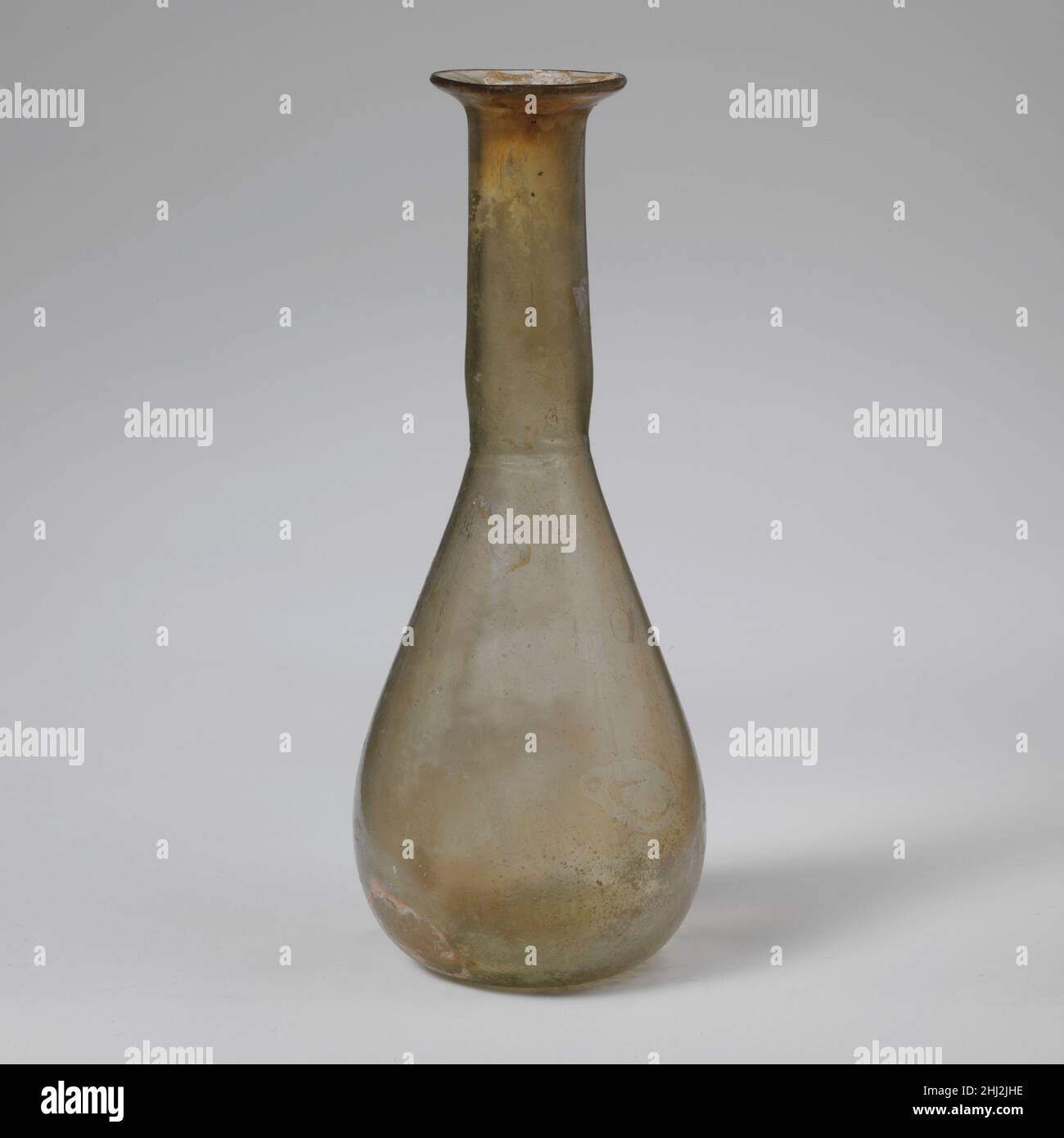 Parfümflasche aus Glas 1st. Jahrhundert n. Chr. römisch Durchscheinend hellgelb grün.einfacher, abgerundeter Rand; abfackelnder Mund; zylindrischer Hals, leicht nach unten ausdehnend und mit Werkzeugnuten um den Boden; länglicher konischer Körper mit konvexen Seiten; leicht konkaver Boden.intakt; einige Blasen und schwarze Verunreinigungen; Flecken von Abstumpfen und Verwitterung; Irideszenz.. Parfümflasche aus Glas 239643 Stockfoto