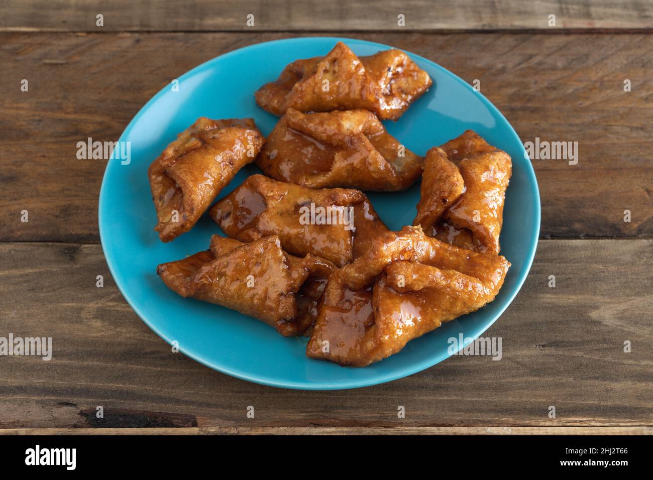 Pestiños. Typische Süßigkeit von Weihnachten und Ostern. Karneval gebratene Süßigkeiten in blauer Platte auf Holzhintergrund. Speicherplatz kopieren. Stockfoto