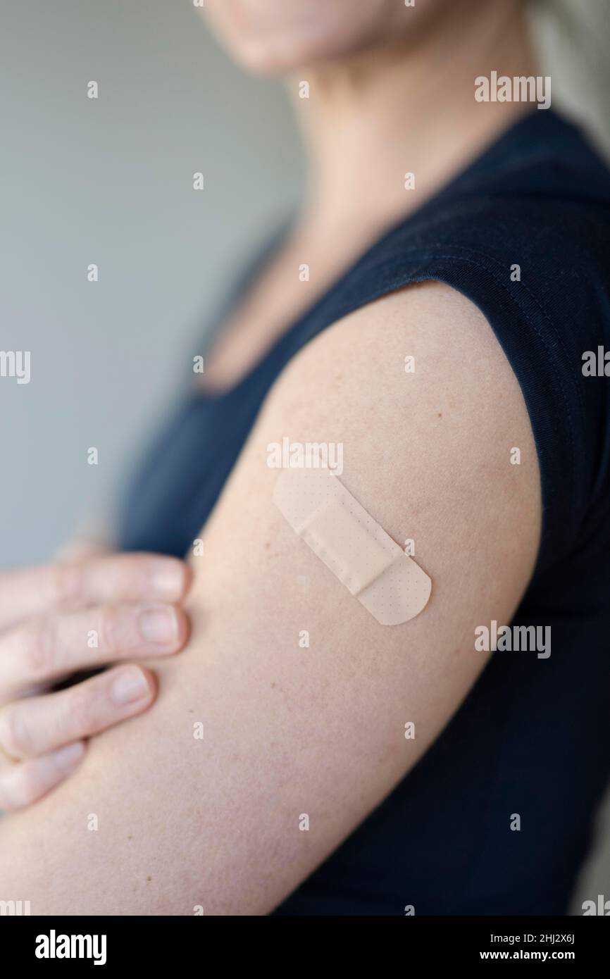 Arm einer Frau mit einem Gips auf ihrem Oberarm nach der Impfung Stockfoto