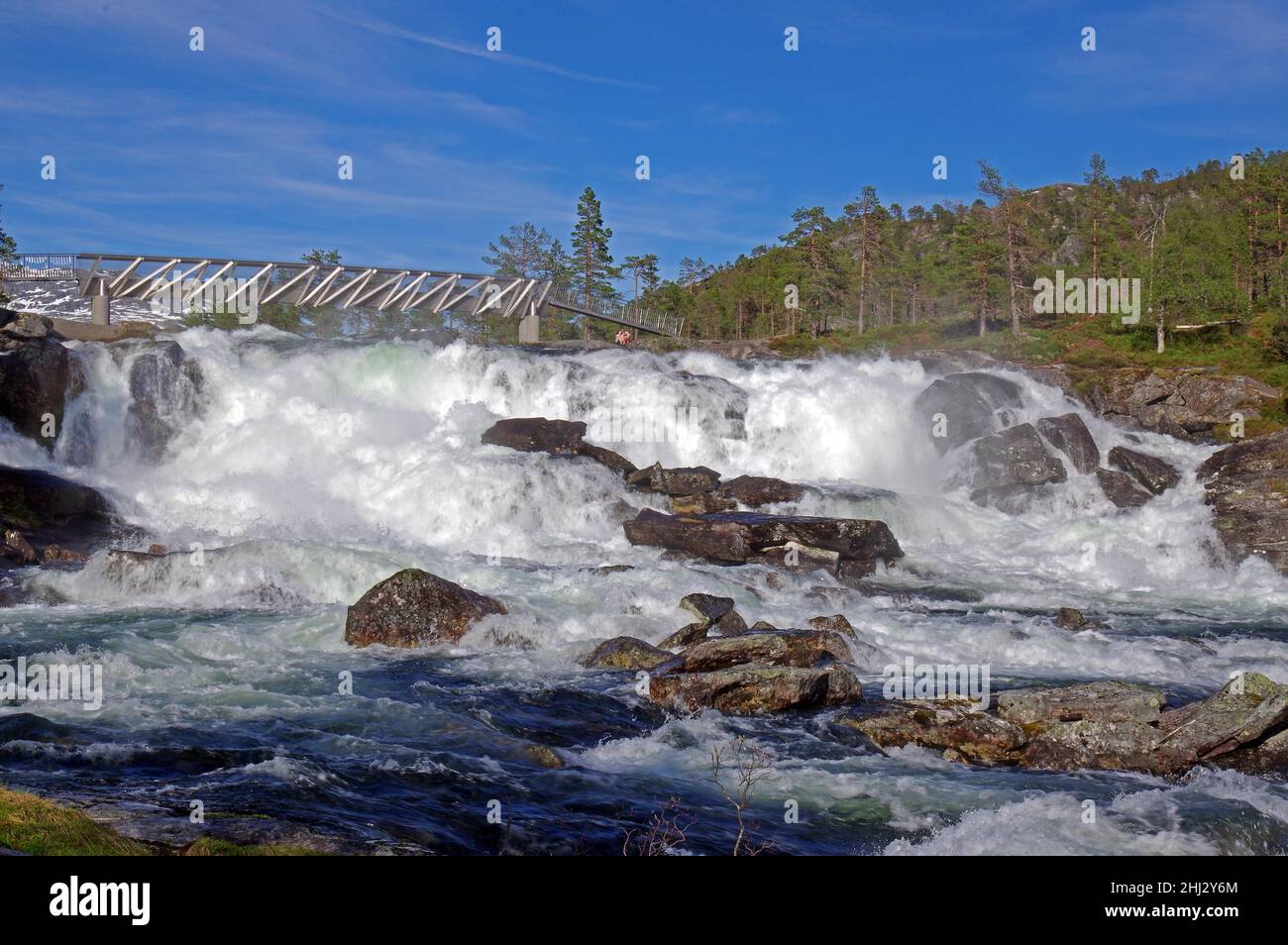 Donnernder Wasserfall, der von einer Fußgängerbrücke überspannt wird, Fossestien, Gaular, Norwegen Stockfoto