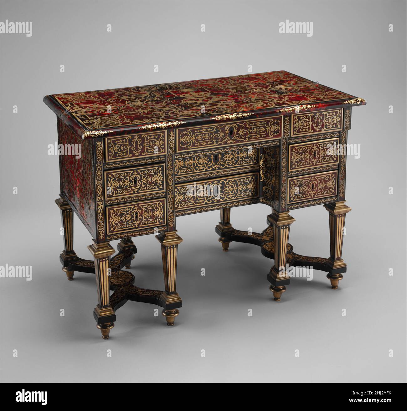 Kleiner Schreibtisch mit Klapptisch (Bürobrisé) ca. 1685 Intarsien von Alexandre-Jean Oppenordt Dutch dieser Schreibtisch und sein Paar wurden 1685 für die Verwendung durch Ludwig XIV. In seinem Arbeitszimmer oder Kleinschrank im Nordflügel des château de Versailles geliefert. Die Form wird als Bureau brisé bezeichnet, wörtlich ein „kaputter Schreibtisch“, da die aufklappbare vordere Hälfte der flachen Oberseite zurückgefaltet oder „gebrochen“ werden kann, um eine schmale Schreibfläche zu offenbaren. Die aufwendige Dekoration auf der Oberseite umfasst das gekrönte Monogramm des Königs mit verschachtelten L's unter einem strahlenden Sonnensymbol, das mit einer jetzt unbestimmten Apollo-Maske graviert ist. Hören Sie den kranken Experten zu Stockfoto Kleiner Schreibtisch mit Klapptisch (Bürobrisé) ca. 1685 Intarsien von Alexandre-Jean Oppenordt Dutch dieser Schreibtisch und sein Paar wurden 1685 für die Verwendung durch Ludwig XIV. In seinem Arbeitszimmer oder Kleinschrank im Nordflügel des château de Versailles geliefert. Die Form wird als Bureau brisé bezeichnet, wörtlich ein „kaputter Schreibtisch“, da die aufklappbare vordere Hälfte der flachen Oberseite zurückgefaltet oder „gebrochen“ werden kann, um eine schmale Schreibfläche zu offenbaren. Die aufwendige Dekoration auf der Oberseite umfasst das gekrönte Monogramm des Königs mit verschachtelten L's unter einem strahlenden Sonnensymbol, das mit einer jetzt unbestimmten Apollo-Maske graviert ist. Hören Sie den kranken Experten zu Stockfoto