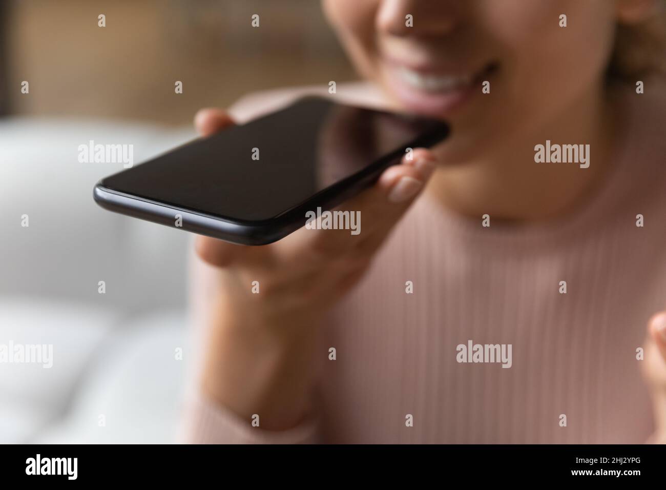 Nahaufnahme die weibliche Hand hält das Smartphone über die Freisprecheinrichtung nahe am Mund Stockfoto