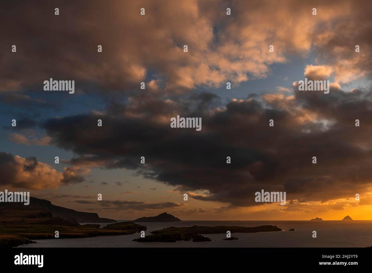 Meeresküste mit den Berggipfeln der Skelligs im Hintergrund und dramatisch bewölktem Himmel, Killarny, County Kerry, Irland Stockfoto