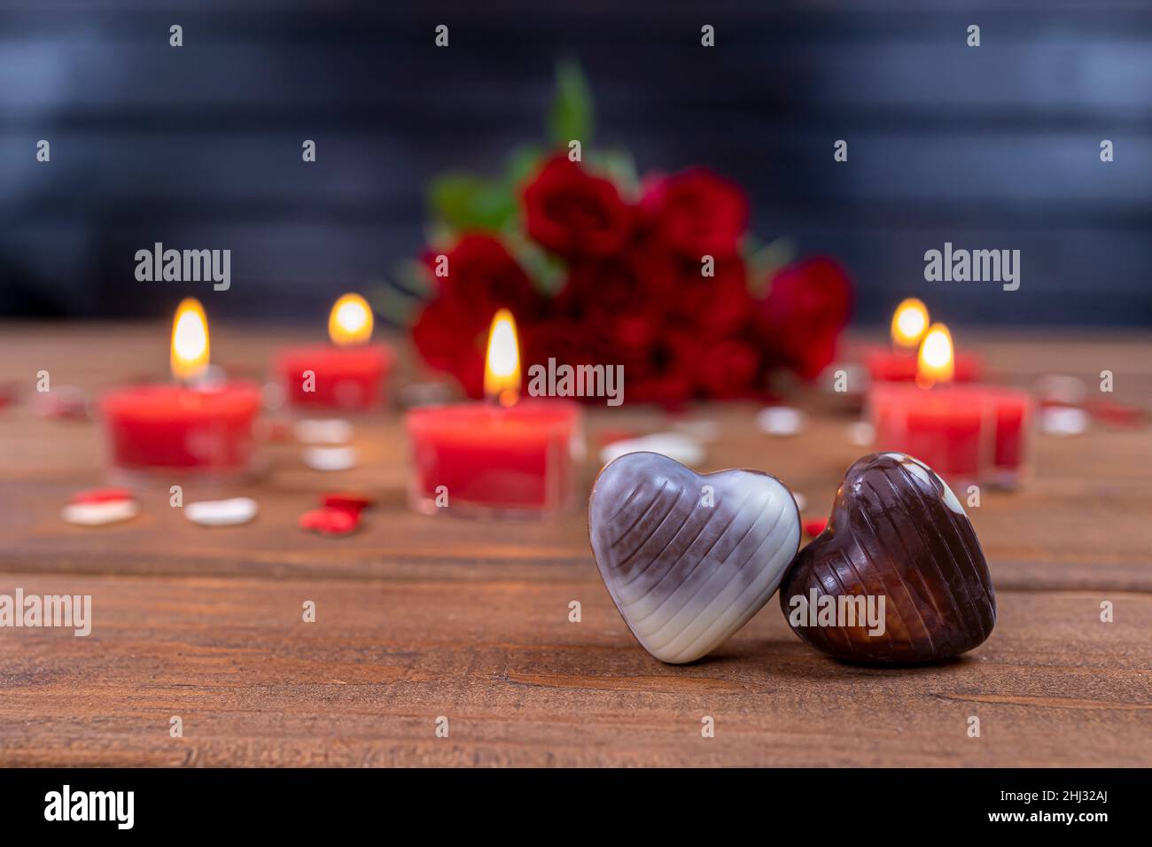 Valentinstag Konzept Schokolade Bonbons herzförmig und rote Rosen mit Kerzen auf Holz. Liebe und Romantik Konzept. Stockfoto