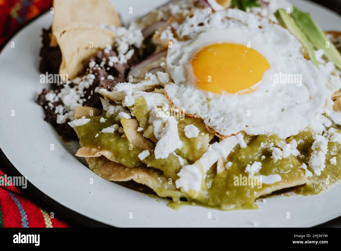 mexikanische grüne Chilaquiles mit Spiegelei, Huhn und würziger grüner Sauce traditionelles Frühstück in Mexiko Stockfoto