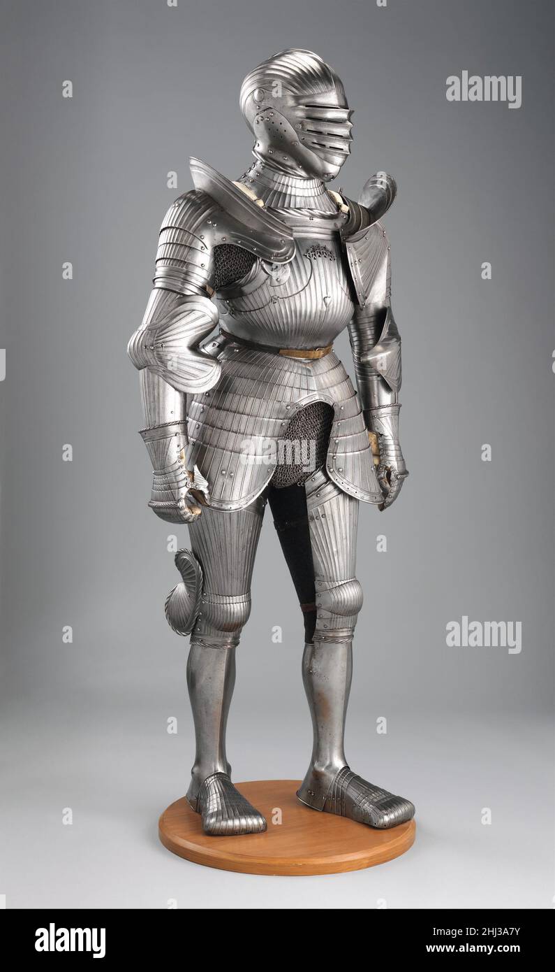 Rüstung ca. 1520 und später Deutsch, Nürnberg um die Wende des 16. Jahrhunderts verließen deutsche Waffler die schlanken Linien des spätgotischen Stils und nahmen die volleren, abgerundeten Formen an, die in Italien bevorzugt wurden. In dem neuen Stil waren die flachen parallelen Kanäle, die fast die gesamte Rüstung bedeckten, nicht nur dekorativ, sondern stärkten das Metall tatsächlich. Dies wird oft als "Maximilian-Stil" bezeichnet, weil es zur Zeit Kaiser Maximilians I. (1459–1519) eingeführt wurde. Geriffelte Rüstung scheint eine Spezialität von Nürnberg gewesen zu sein.auf dieser Rüstung die zweiteilige Konstruktion des Brustpanzers Stockfoto