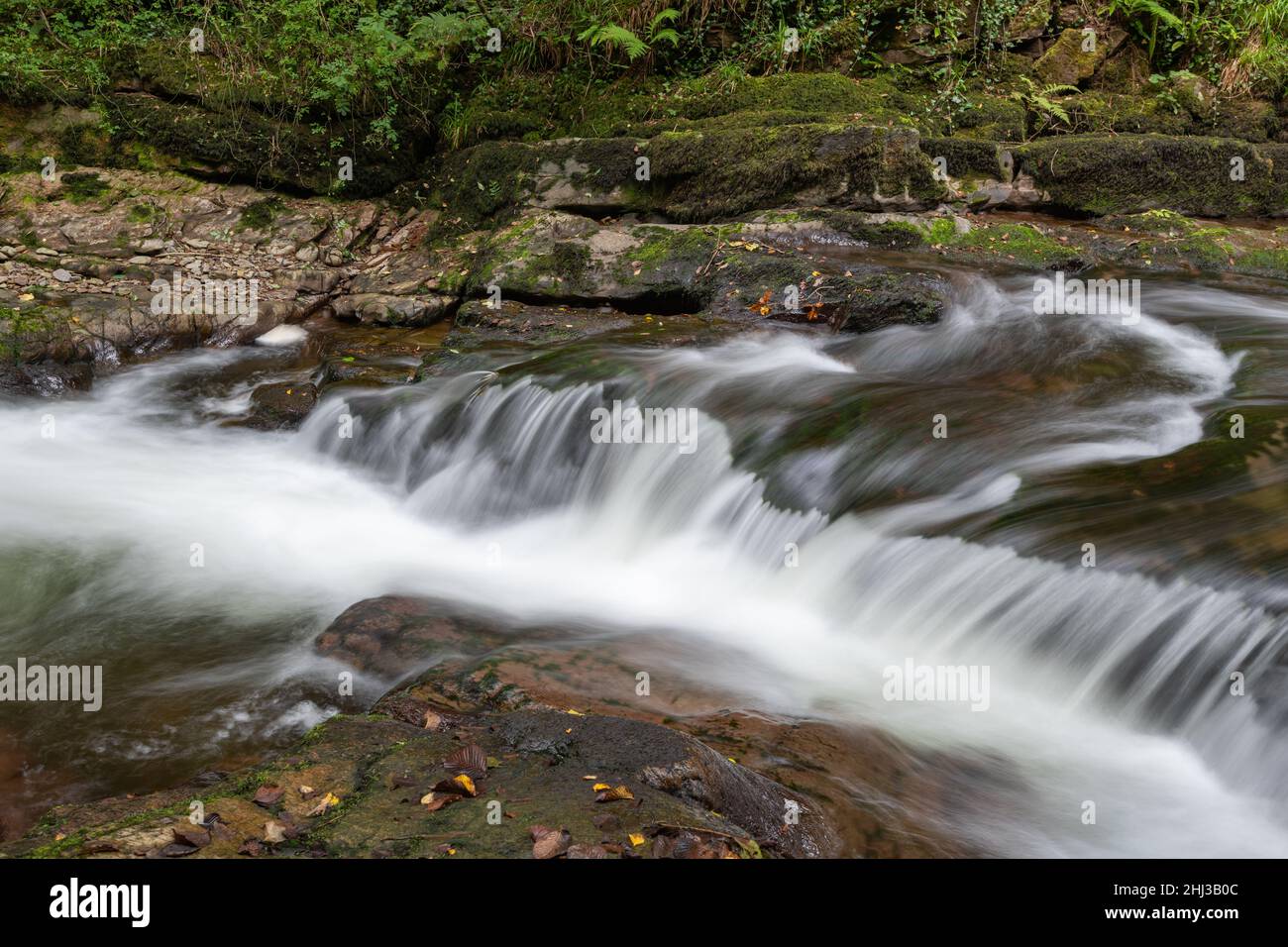 Lange Exposition eines Wasserfalls auf dem East Lyn Fluss Fließt durch den Wald bei Watersmeet im Exmoor Nationalpark Stockfoto